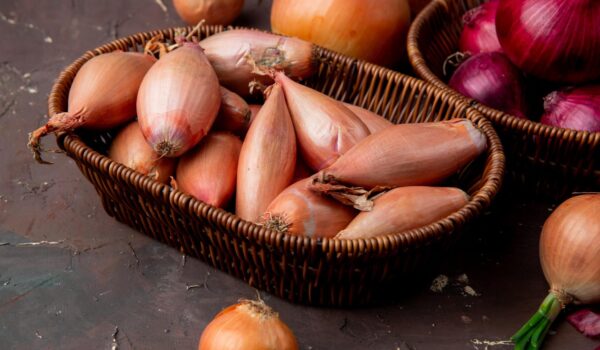 close up view basket full onions maroon background