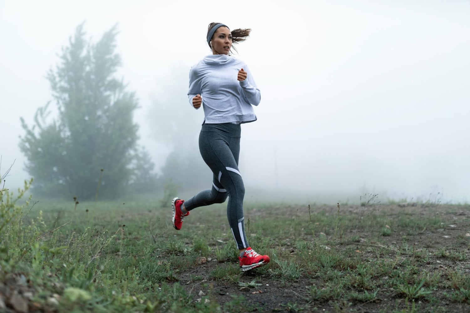 determined female runner jogging through misty filed morning copy space
