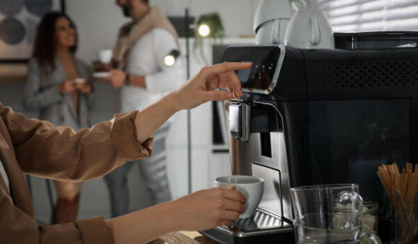 woman preparing fresh aromatic coffee with modern machine in office, closeup