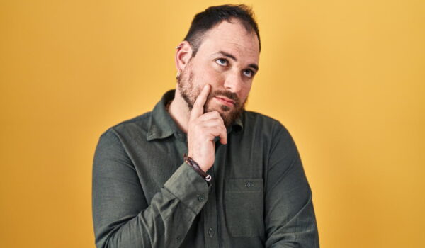 plus size hispanic man with beard standing yellow background with hand chin thinking about question pensive expression smiling with thoughtful face doubt concept