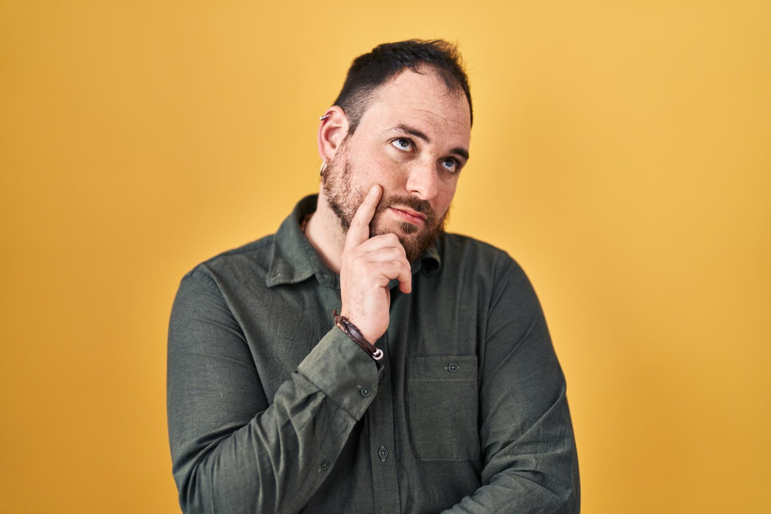 plus size hispanic man with beard standing yellow background with hand chin thinking about question pensive expression smiling with thoughtful face doubt concept