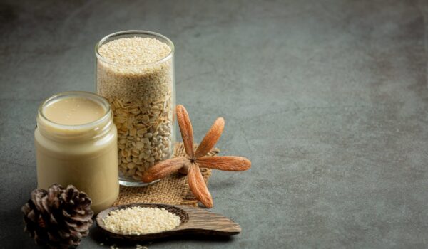 tahini and sesame seeds on dark background